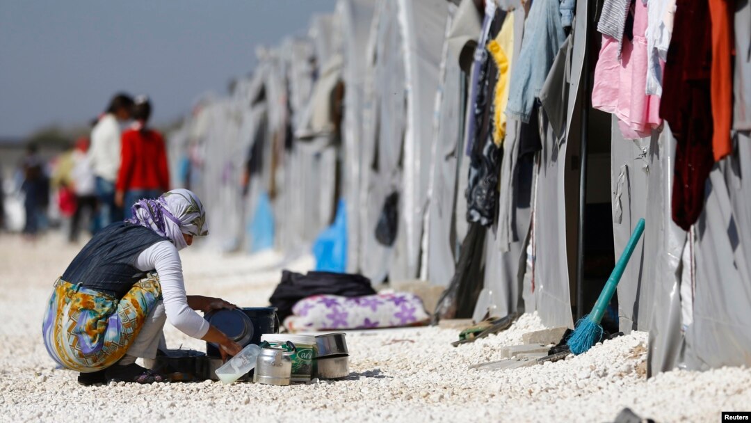FILE - A Kurdish refugee woman from the Syrian town of Kobani washes dishes at a refugee camp in the border town of Suruc, Sanliurfa province, Turkey, Nov. 11, 2014. 