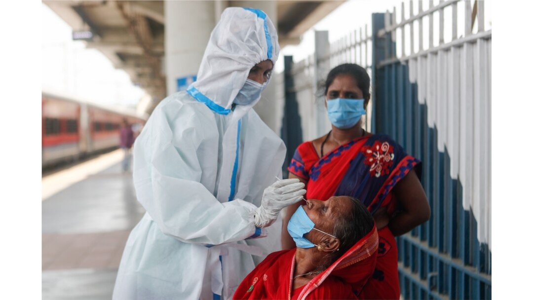 A healthcare worker in personal protective equipment collects a swab sample from a woman, amidst the spread of the coronavirus disease, at a railway station in Mumbai, India, April 16, 2021.