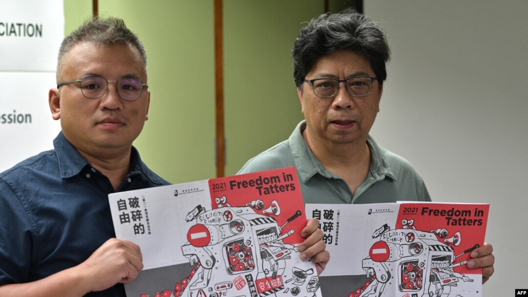 香港記者協會主席陳朗昇(左)與報告主筆楊健興手持香港新聞自由年度報告《破碎的自由》。 （2021年7月15日）