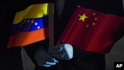 El canciller de Venezuela, Jorge Arreaza, sostiene las banderas de Venezuela y China mientras llegan especialistas médicos y suministros de China al Aeropuerto Internacional Simón Bolívar. en La Guaira, Venezuela. Marzo 30, 2020.