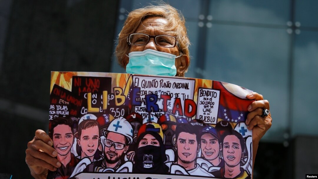 Una mujer sostiene un cartel con imágenes de personas que murieron durante las protestas del 2017, mientras asiste a una manifestación contra los cambios en las sanciones de Estados Unidos en Caracas, el 18 de mayo de 2022.