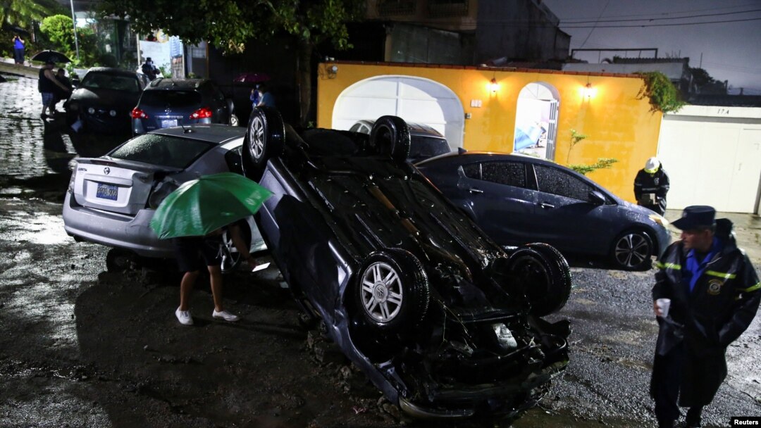 Personas observan vehículos dañados durante una inundación repentina causada por fuertes lluvias debido a la tormenta tropical Bonnie, en San Salvador, El Salvador, 2 de julio de 2022. REUTERS/José cabezas