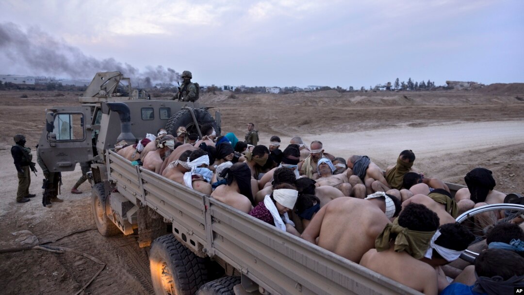 Soldados israelíes junto a un camión lleno de detenidos palestinos atados y con los ojos vendados, en Gaza, el viernes 8 de diciembre de 2023. 