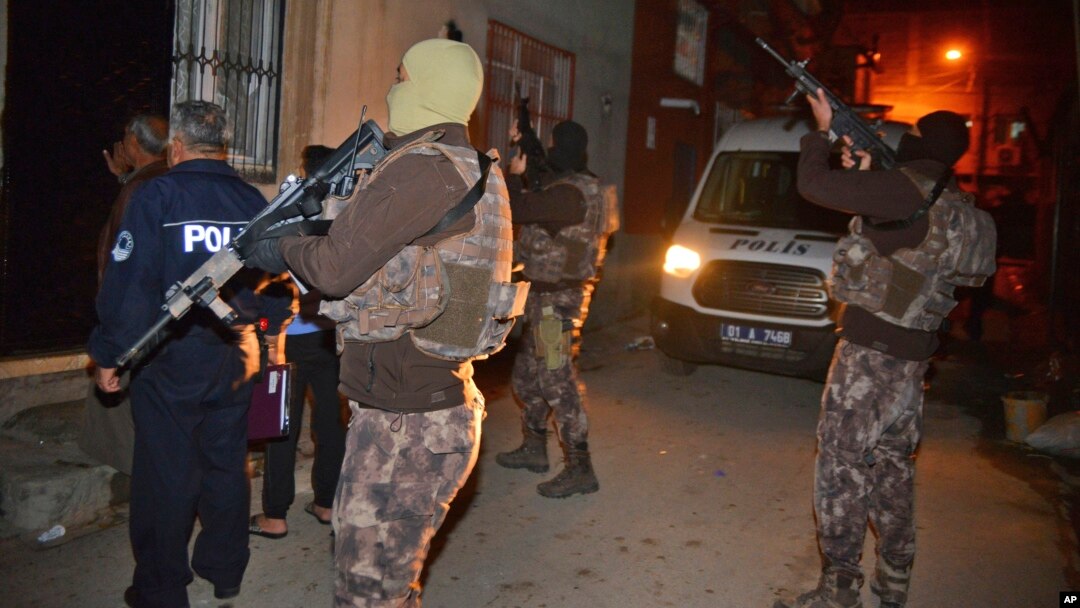 Masked Turkish police officers secure the perimeter outside a house during an operation to arrest people for alleged links to Islamic State group in Adana, Turkey, Nov. 10, 2017. 