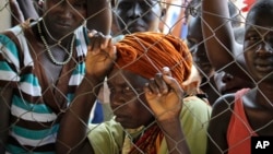 FILE - Women stand outside a U.N. Refugee Agency (UNHCR) site distributing soap, blankets and other items in Yei, in southern South Sudan, Nov. 14, 2016.