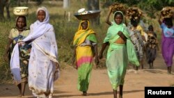 FILE - Sudanese refugees from Darfur carry goods and firewood near the village of Sam Ouandja, in the remote northeast of the Central African Republic, Dec. 6, 2007. Some 1,500 refugees from Darfur in the CAR are scheduled to return home by the end of the year.
