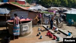Rohingya Muslim men collect water from a well at Unchiprang refugee camp near Cox's Bazar, in Bangladesh, Nov. 16, 2018.