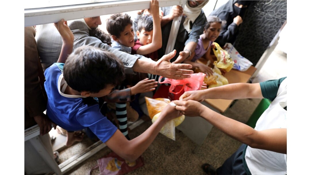 FILE - People crowd to get food rations from a charity kitchen in Sana'a, Yemen, July 20, 2020.