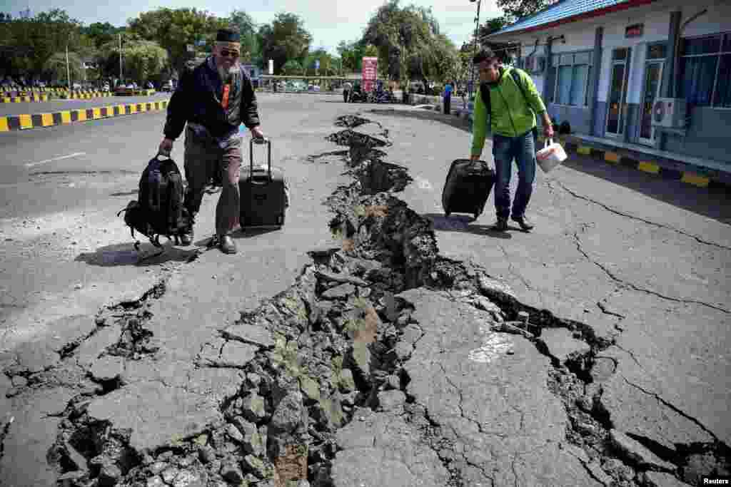 People walk on a road damaged by yesterday's large earthquake at Kayangan Port in Lombok, Indonesia, in this photo taken by Antara Foto.