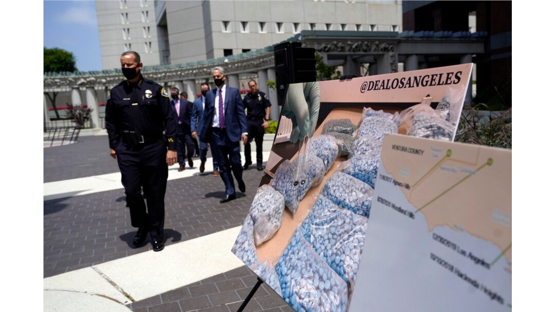 Los funcionarios pasan frente a imágenes de drogas ilegales frente al edificio federal Edward R. Roybal, el jueves 13 de mayo de 2021, en Los Ángeles, California.