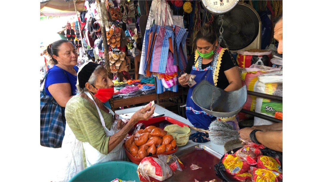 La comerciante Rina Castillo despacha alimentos básicos a los clientes que abarrotaron su mercado.