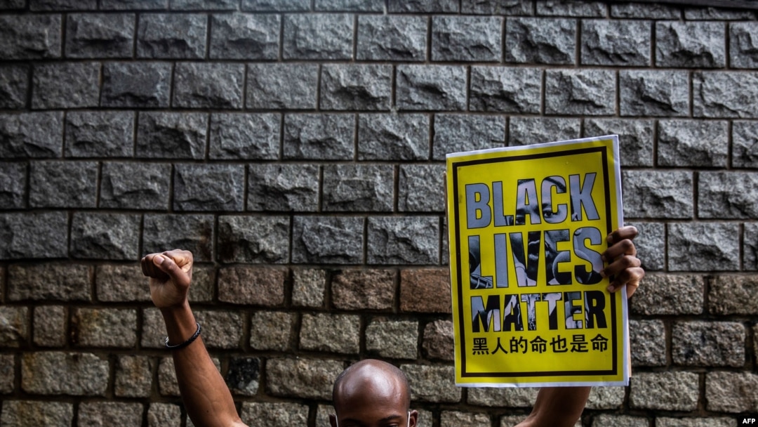 FILE - A protester holds a Black Lives Matter sign outside the U.S. consulate during a demonstration against racism and police brutality in Hong Kong, June 7, 2020.