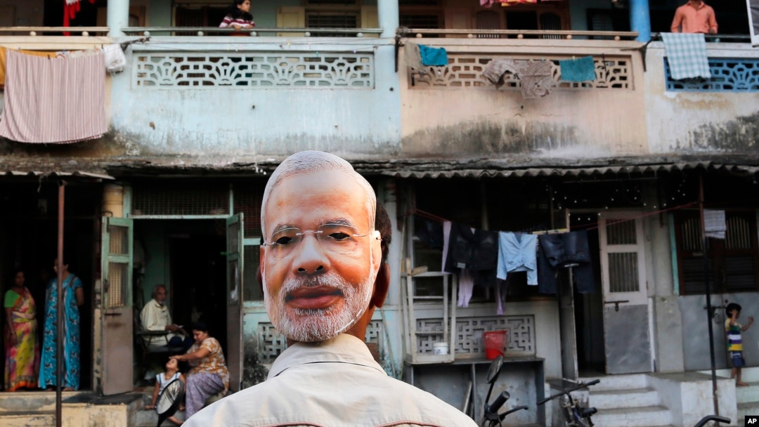 FILE - A supporter of India's main opposition Bharatiya Janata Party (BJP) wears a mask depicting the face of Prime Minister candidate Narendra Modi, during an election rally in Mumbai, India, Wednesday, April 9, 2014.