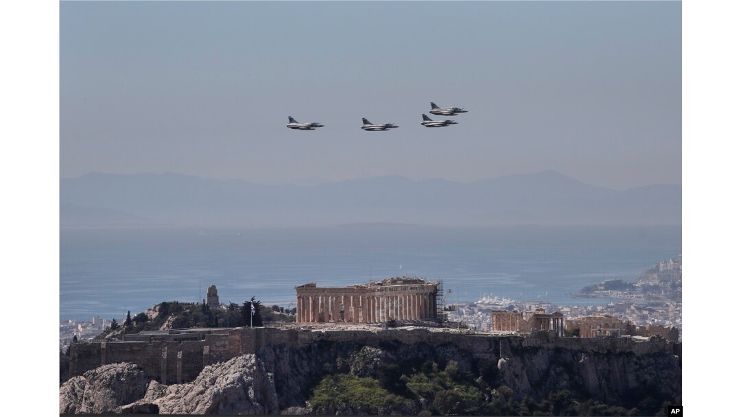 A formation of Greek fighter jets flies over the temple of the Parthenon, on the ancient Acropolis hill during a military parade in Athens March 25, 2017.