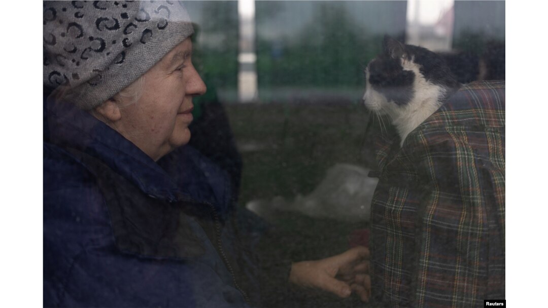 A woman who has been evacuated by the Red Cross from the Donetsk area sits with her cat after their bus stopped at a gas station on their way to Lviv, outside Dnipro, Ukraine April 21, 2022. (REUTERS/Jorge Silva)