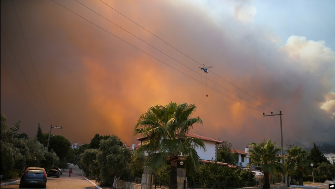 A helicopter flies as a fire engulfs the area in Oren, near Bodrum, Turkey, Aug. 3, 2021.