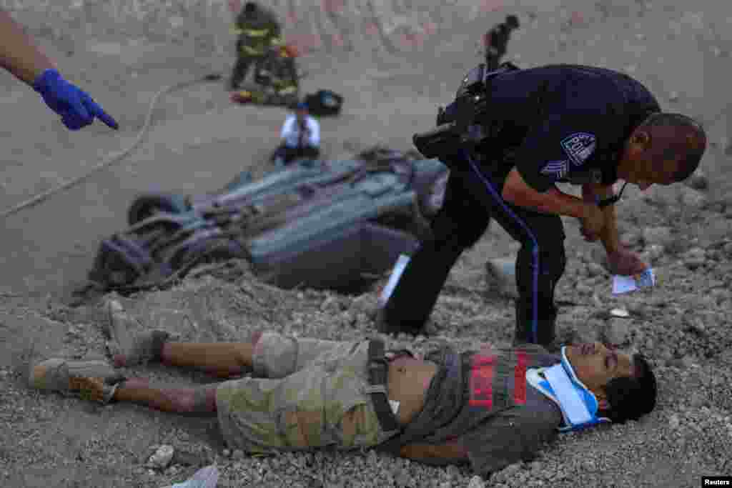 A policeman from the city of La Joya stands over an 18-year-old male who lies injured after crashing his vehicle while transporting two men and a woman who illegally crossed into the U.S. border from Mexico in Penitas, Texas, U.S. August 30, 2018.