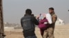 An Iraqi soldier carries a wounded girl into Mosul's only clinic for treatment before transport to a hospital, Nov. 27, 2016. (H. Murdock/VOA)