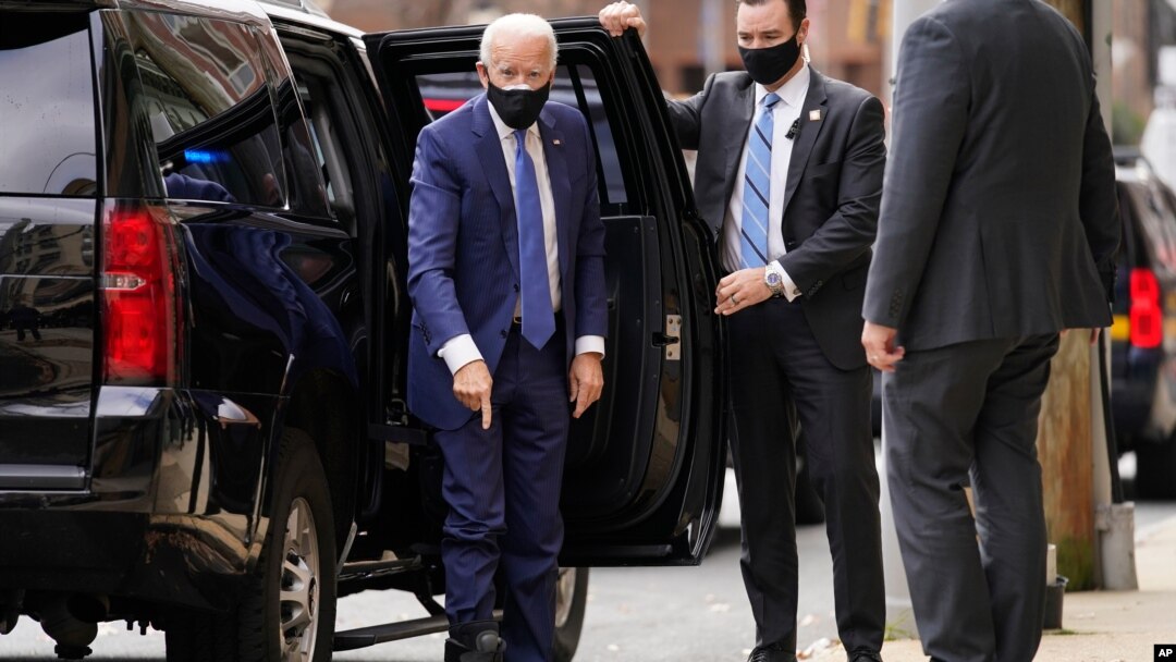 El presidente electo Joe Biden señala su bota ortopédica al llegar al Teatro Queen en Wilmington, desde donde realizó una reunión virtual con trabajadores y empresarios.