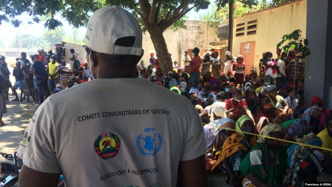 Mfanyakazi wa Shirika la Chakula Duniani, WFP, na watu waliolazimika kukimbia makazi yao wakisubiri maelekezo ya utaratibu wa kupatiwa Chakula huko Cabo Delgado. Picha hii imepigwa Aprili 5, 2021.