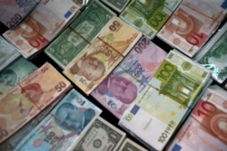 FILE - Turkish liras, center, featuring images of Turkish Republic founder Mustafa Kemal Ataturk, among other foreign currency, Istanbul, June 8, 2015.