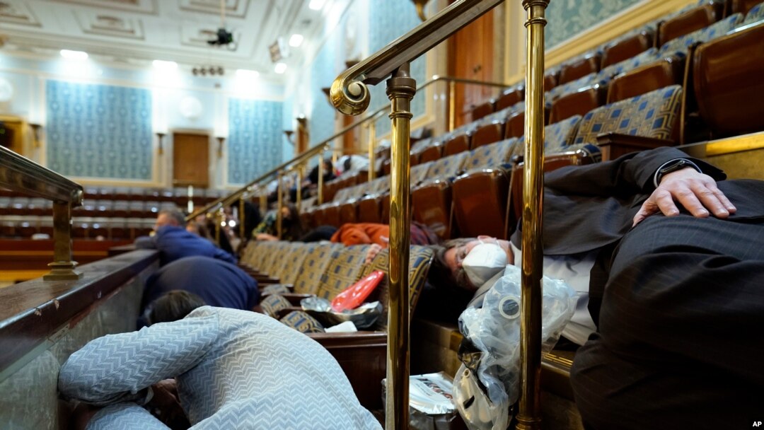 La gente se refugia en la galería de la Cámara mientras los manifestantes intentan irrumpir en la Cámara de la Cámara en el Capitolio de los Estados Unidos el miércoles 6 de enero de 2021 en Washington.