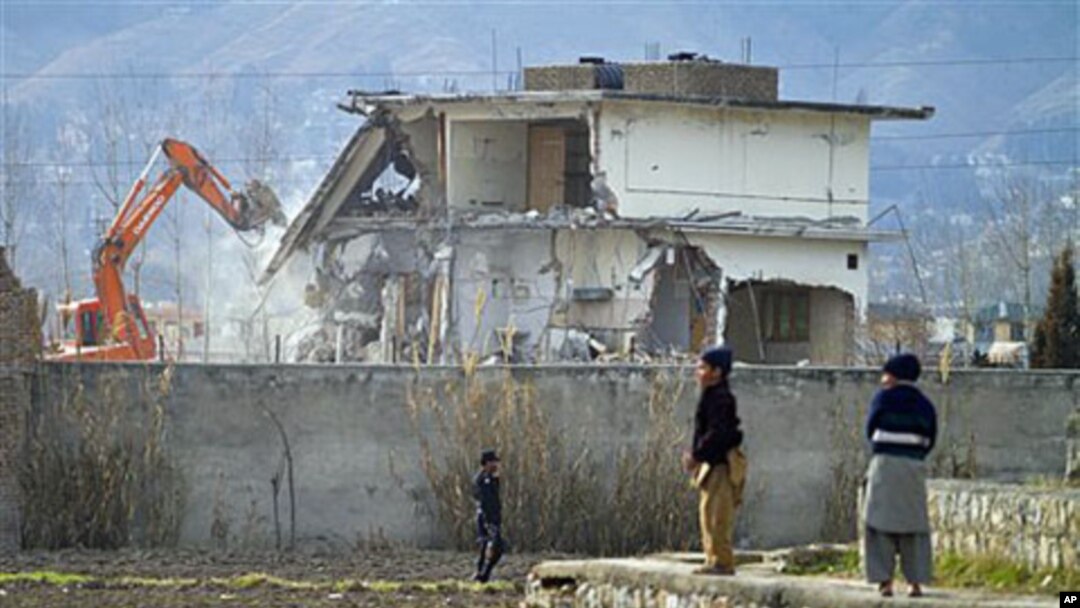 A police commando stands guard as authorities use heavy machinery to demolish Osama bin Laden's compound in Abbottabad, Pakistan, February 26, 2012.