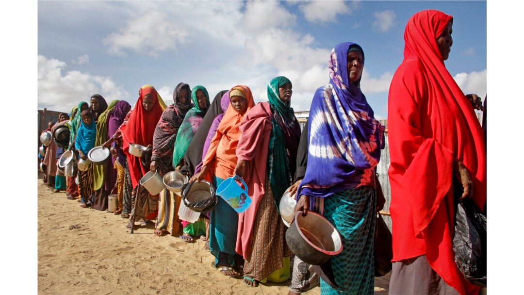 FILE - Newly-arrived women who fled drought queue to receive food distributed by local volunteers at a camp for displaced persons in the Daynile neighborhood on the outskirts of the capital Mogadishu, in Somalia, May 18, 2019.