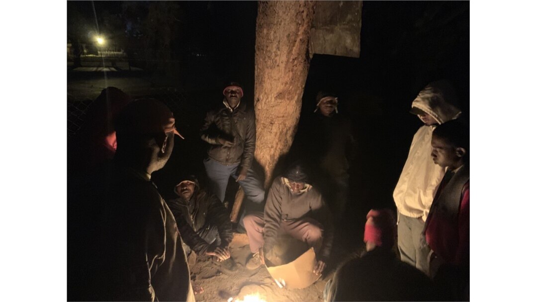 Applicants outside a Harare passport office use fire to keep cold at bay, June 21, 2019. (C. Mavhunga/VOA)