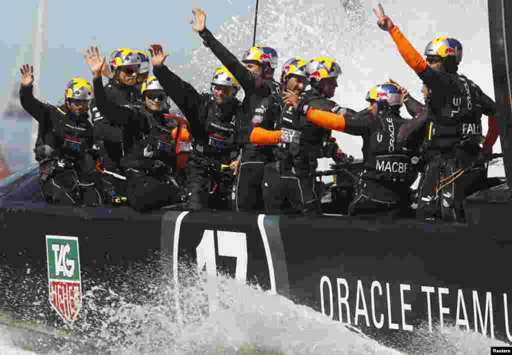 Crew from Oracle Team USA wave to fans after defeating Emirates Team New Zealand during Race 16 of the 34th America's Cup yacht sailing race in San Francisco, California, Sept. 23, 2013.