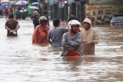 Indonesian people wade through floodwaters in Jatibening on the outskirt of Jakarta, Indonesia, Jan. 1, 2020.