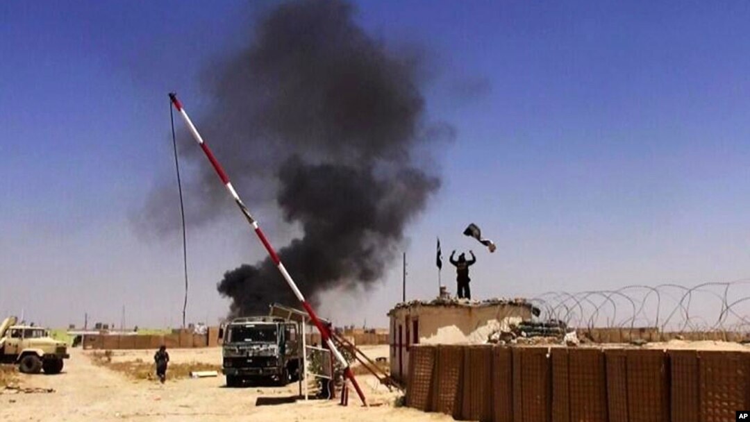 This image posted on a militant news Twitter account on June 12, 2014 shows militants from the al-Qaida-inspired Islamic State, formerly known as the Islamic State in Iraq and the Levant (ISIL), raising their flag at an army base in Ninevah Province, Iraq.