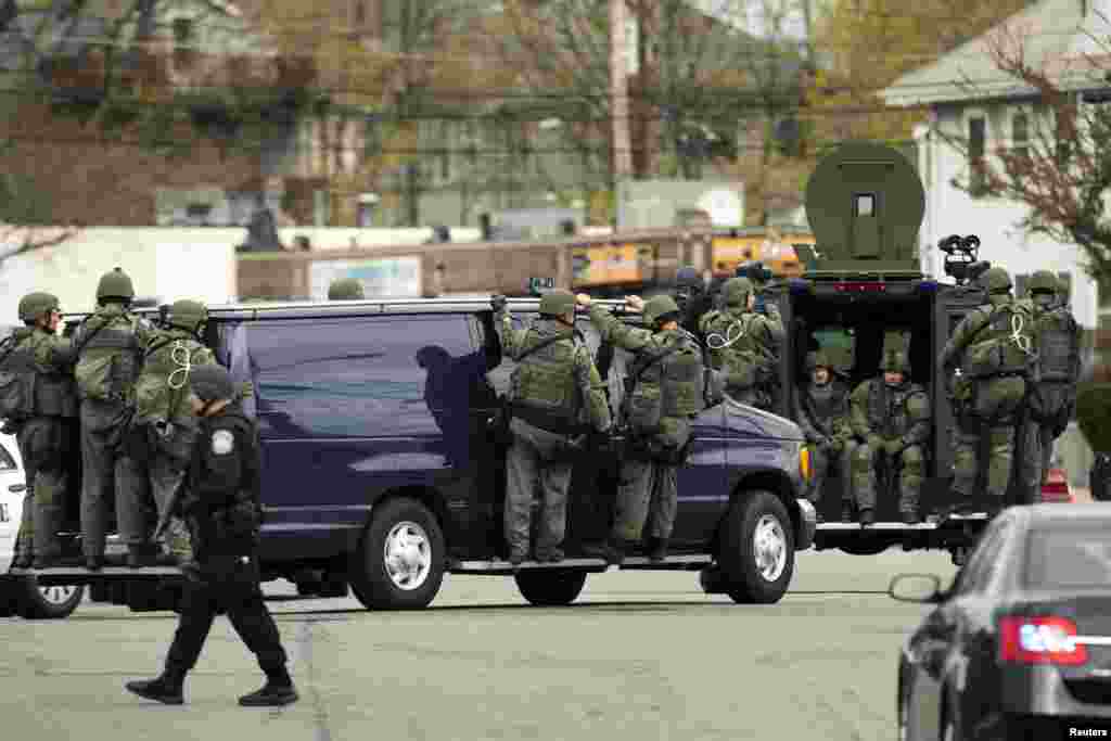 Law enforcement officers in tactical gear enter the search area for Dzhokar Tsarnaev, the one remaining suspect in the Boston Marathon bombing, in Watertown, Massachusetts, April 19, 2013.