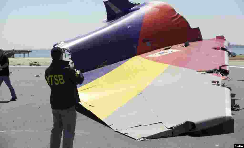 A National Transportation Safety Board (NTSB) investigator looks at the tail section of the Asiana Airlines Flight 214 that crashed at San Francisco International Airport, July 7, 2013. (NTSB)