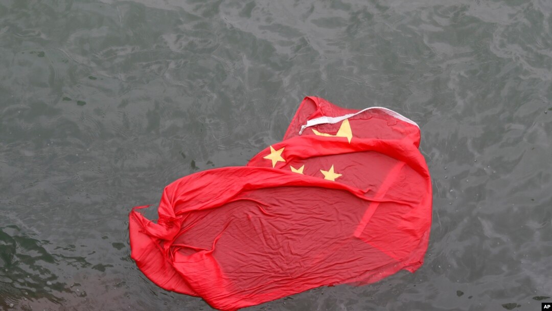 A Chinese flag floats on the surface it was thrown in the water by protesters during a demonstration in Hong Kong, Saturday, Aug. 3, 2019. 