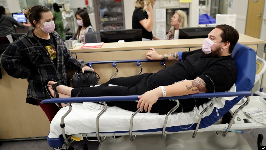 Donnie Cardenas, right, waits in an emergency room hallway alongside roommate Torrey Jewett, left, as he recovers from the flu at the Palomar Medical Center in Escondido, Calif., Jan. 10, 2018.