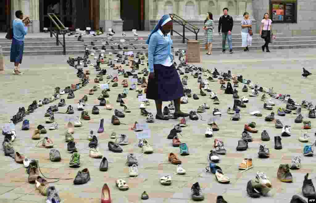 Catholic Agency For Overseas Development's (CAFOD) Sister Clara from Zambia walks through shoes displayed outside Westminster Cathedral in central London to promote Pope Francis' refugee campaign. The campaign is calling for world leaders to back global agreements aimed at assisting refugees and migrants.
