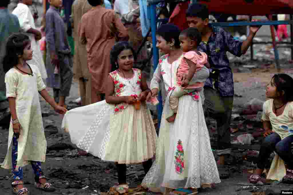 Siblings in new dresses stand beside a swing at a playground in a low-income neighborhood on the last day of Eid al-Adha celebrations in Karachi, Pakistan.