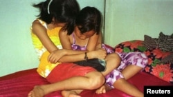 FILE - Two Vietnamese girls, aged eight and 10, sit on a bed in a brothel inthe Cambodian village of Svay Pak, near Phnom Penh.