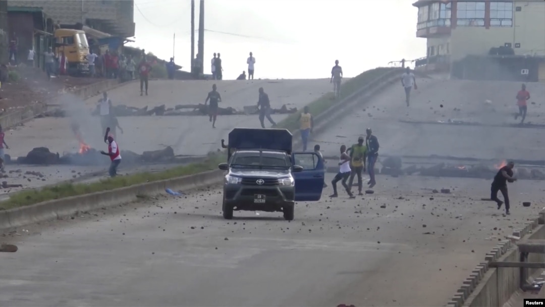 Protesters throw stones at a riot police vehicle on a main road in Sonfonia District in Conakry, Guinea, Oct. 14, 2019, in this still image taken from video. 