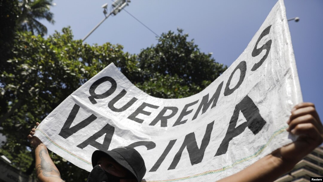 A man holds a banner reading "We want vaccine" during a protest against new measures implemented to curb the spread of the coronavirus disease in Rio de Janeiro, Brazil, March 26, 2021.