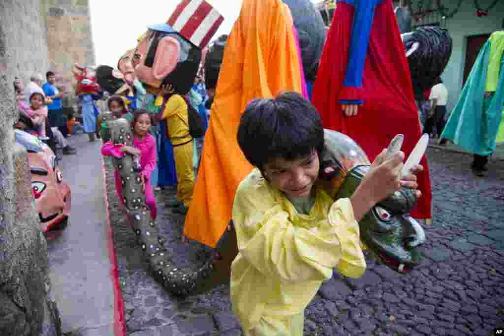 Children carry a snake made out of rags and paper as they take part in the traditional dance of "Los Gigantes," or "The Giants," during Christmas celebrations on Christmas Eve in Antigua Guatemala, Dec. 24, 2014.