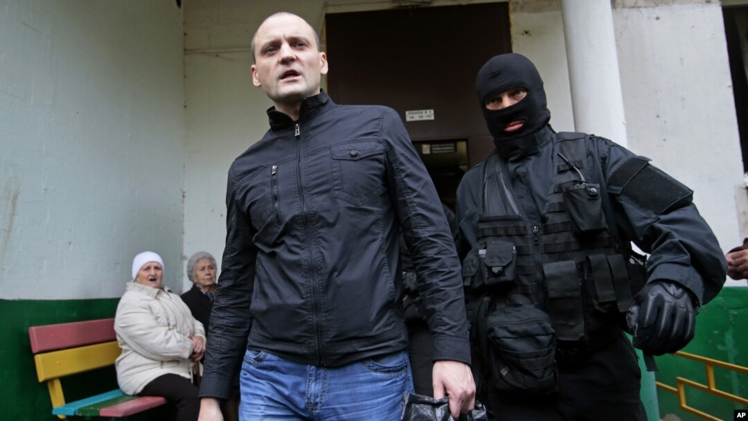 A police officer escorts Russian opposition leader Sergei Udaltsov, center, for questioning in Moscow, October 17, 2012.