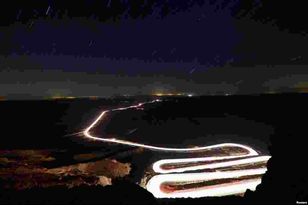 Cars drive through Ramon Crater during the Perseid meteor shower near the town of Mitzpe Ramon, southern Israel, Aug. 12, 2018.