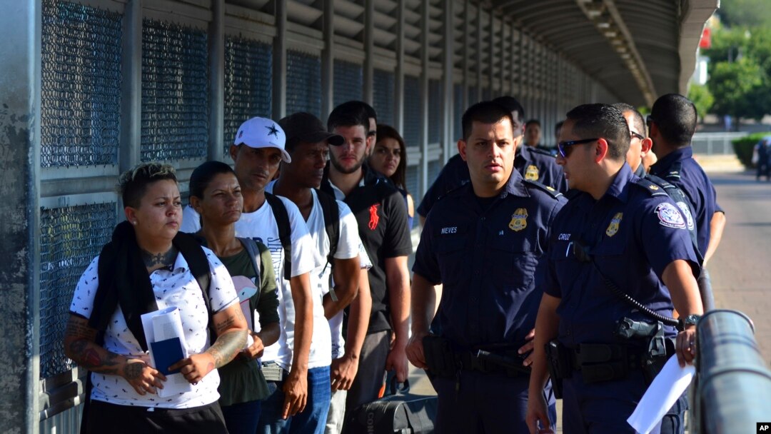 US Customs and Border Patrol officials wait to hand asylum-seekers over to Mexican officials as they are returned under the so-called Remain in Mexico program, on the international bridge between Laredo, Texas, and Nuevo Laredo, Mexico, July 10, 2019. 