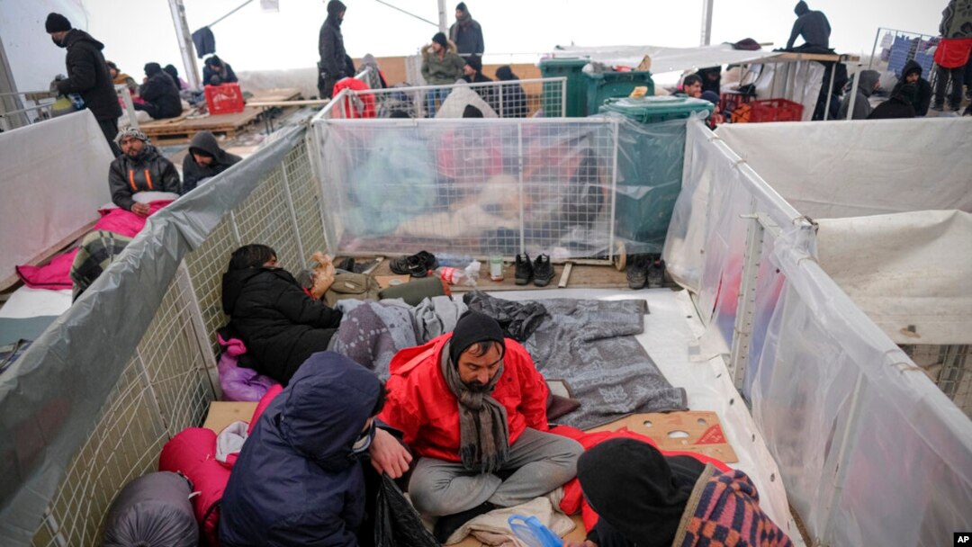 Migrants sit in a temporary shelter at the Lipa camp northwestern Bosnia, Dec. 26, 2020, where hundreds of migrants are stranded in a burned-out, squalid camp in Bosnia as heavy snow fell in the country and temperatures dropped.