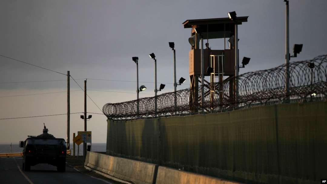 FILE - A U.S. soldier stands in the turret of a vehicle with a machine gun, left, as a guard looks out from a tower at the Guantanamo Bay prison in Cuba, March 30, 2010.