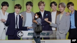 韩国首尔，一名戴着口罩的女子走过一块展示韩国K-Pop组合防弹少年团（BTS）的广告牌（2020年9月30日）。