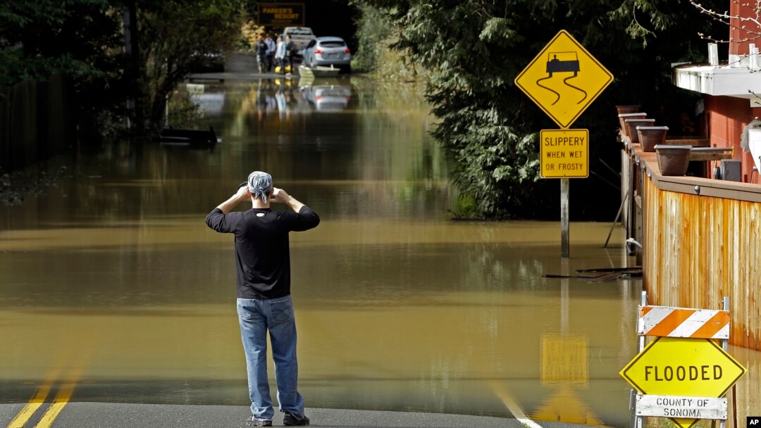 A man photographs a flooded street, Feb. 10, 2017, in Guerneville, Calif. The Russian River rose above its flood stage again Friday. More rain is forecast for the weekend.