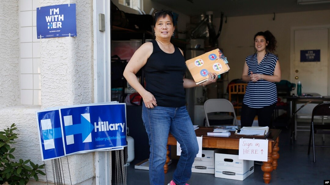 Cynthia Ameli, center, a Chinese-American, picks up materials from Sarah Gibson before heading out to canvass for presidential candidate Hillary Clinton in Las Vegas, Feb. 12, 2016.